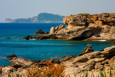 Blue sea with clear water and a rocky shore in the distanceの写真素材
