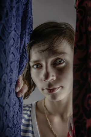 Portrait of a girl with clothes. A beautiful girl looks into a wardrobe with clothes. Green eyes.の写真素材