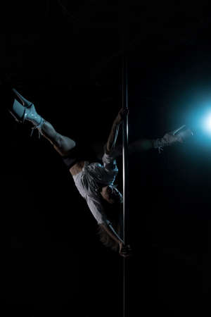Silhouette of a girl on a pole. Aerial acrobatics. Pole dance. A beautiful dancer. Studio with a dark background. Blue Lantern. Silhouette of a beautiful girl.の写真素材