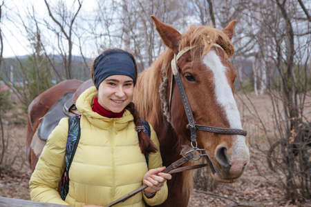 A beautiful girl stands with a horse. Friendship between a girl and a horse. Portraits of a girl and...