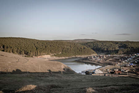 Beautiful mountain landscape at sunset. Village in the valley. Forests grow on the slopes of the...