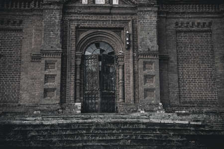An old beautiful and scary abandoned church. Brick walls. Gloomy gothic atmosphere. Evening light.の写真素材
