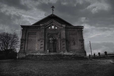 An old beautiful and scary abandoned church. Brick walls. Gloomy gothic atmosphere. Evening light.の写真素材