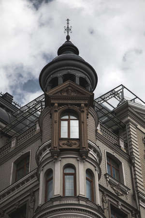 A beautiful old house with a tower and large windows. Gray cloudy sky. Ancient architecture.