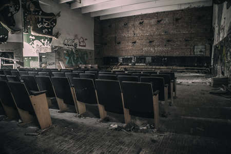 An old hall with seating in an abandoned cinema. Abandoned broken wooden chairs. An old abandoned cinema.の写真素材