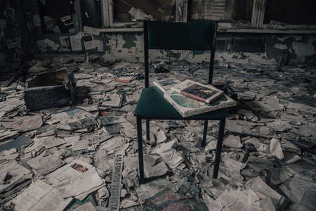 An old abandoned library. Lots of books on the floor. A ray of light from the window. A chair in the middle of the room. Scary old abandoned library.の写真素材