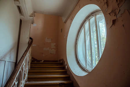 A beautiful round window in an old abandoned hospital. Ancient staircase. The interior of an abandoned building. Beautiful ancient architecture.の写真素材