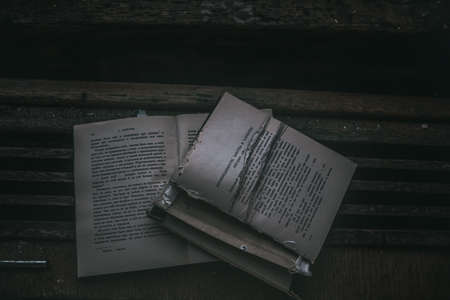 An old book with a torn page lies in an abandoned building. Gloomy atmosphere. An old book....