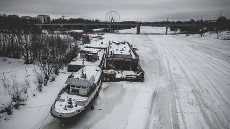 Old rusty abandoned ships on a frozen river. winter landscape. Abandoned technology. Old shabby ships.の写真素材