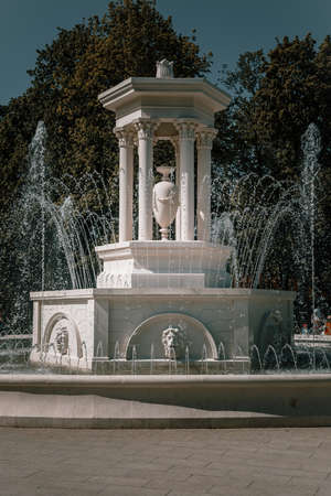 Beautiful white stone fountain. Sunny summer day. green trees. blue sky. beautiful architecture.