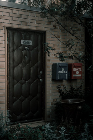 Old abandoned mailboxes on a brick wall. Shabby walls. USSR legacy. beautiful green plants. dark atmosphere.の写真素材