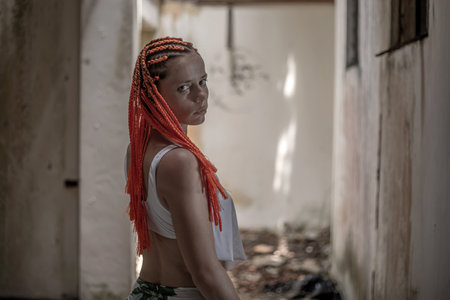 Portrait of a beautiful young woman with red dreadlocks in an abandoned buildingの写真素材