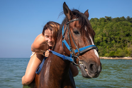 Beautiful young woman with a horse on the beach on a sunny dayの写真素材