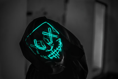 Creepy man in death costume with glowing skull on dark backgroundの写真素材