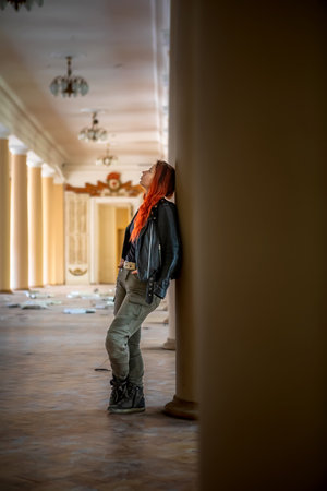 Beautiful red-haired girl in a leather jacket in the interior of the buildingの写真素材