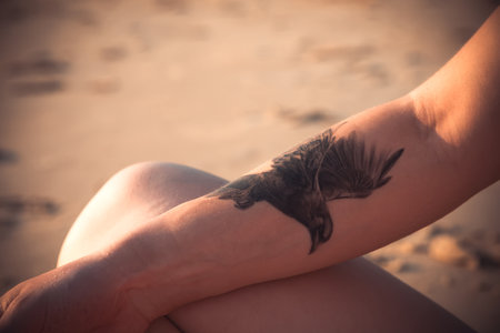 Tattoo on the arm of a young woman on the beachの写真素材