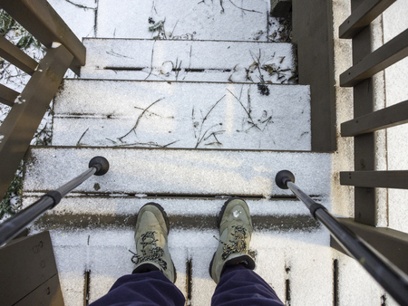 Hiker's boots and sticks on stairs with snow