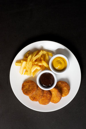 Chicken nuggets with french fries and sauce on a white plate.の写真素材
