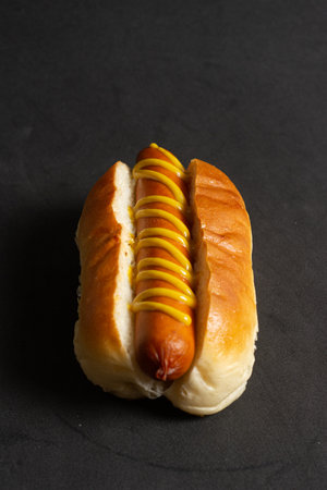 Hot dog with mustard on a black background. Close-up.の写真素材