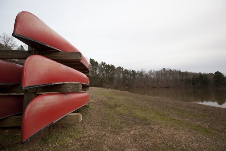 Red canoes on a rack by a lake の写真素材
