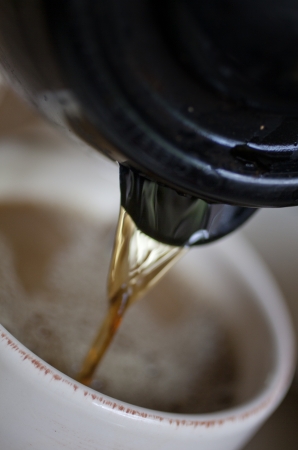 Coffee pouring out of a coffee pot spout into a mug.の写真素材