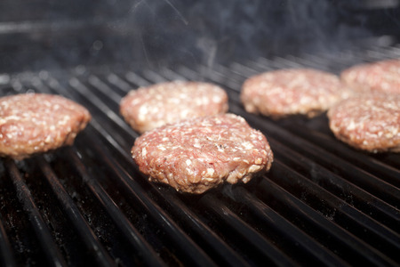 Hamburger patties cooking on a grill の写真素材