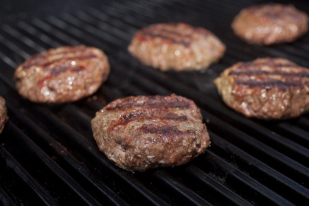 Hamburger patties cooking on a grill の写真素材