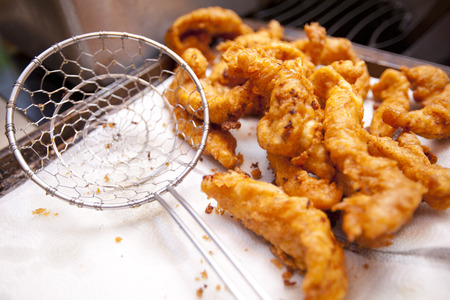 Crispy fried chicken tenders cool on a paper towel after being cooked in a deep fryer.の写真素材