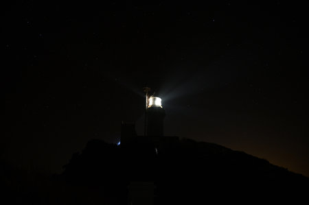A view of a lighthouse at night with a starry sky.の写真素材