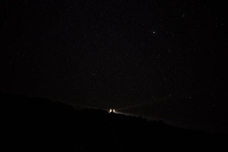 Night sky with stars and the silhouette of a woman on top of a mountain