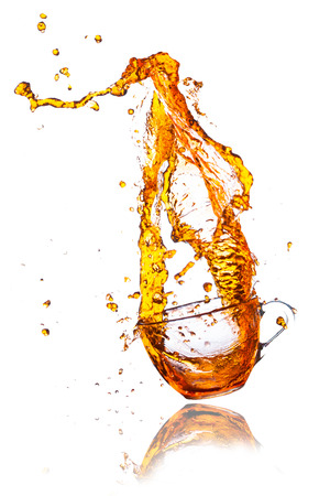 Brown splashes out drink from glass on a white background の写真素材