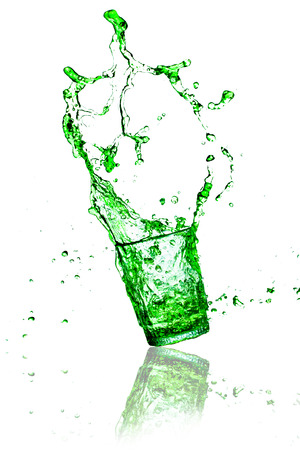 green splashes out drink from glass on a white background の写真素材