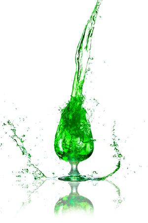 green splashes out drink from glass on a white background の写真素材