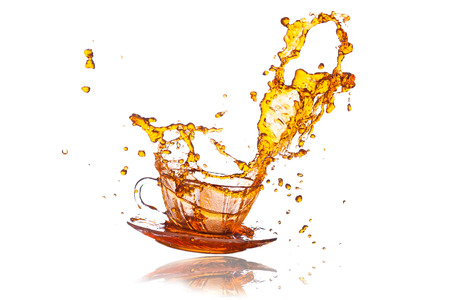 Brown splashes out drink from glass on a white background の写真素材