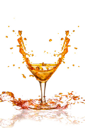 Brown beverage splash out of the glass の写真素材