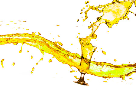Yellow splashes out drink from glass on a white background の写真素材
