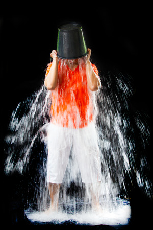 man pour a bucket of ice topped their head on a black の写真素材