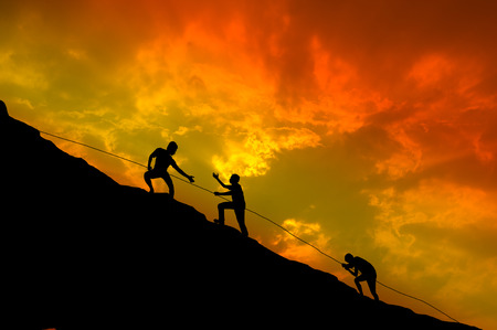 Silhouettes of people are climbing.の写真素材