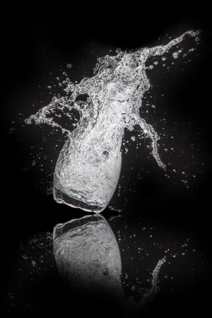Splash water out of a glass on a black background.の写真素材