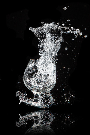 Splash water out of a glass on a black background.の写真素材