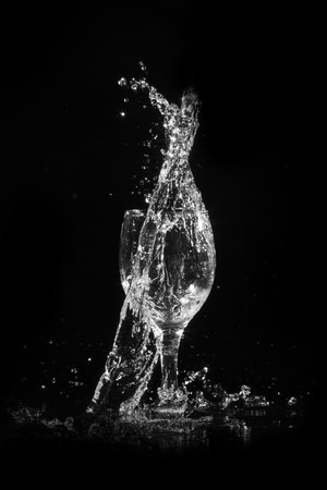 Splash water out of a glass on a black background.の写真素材