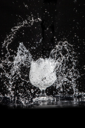 Splash water out of a glass on a black background.の写真素材