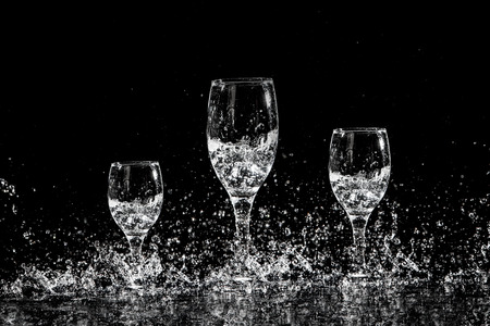 Splash water out of a glass on a black background.の写真素材