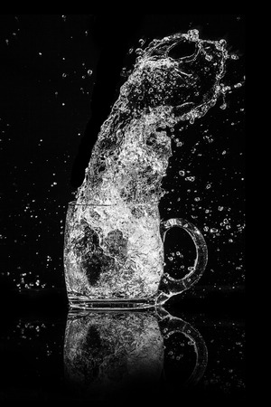 Splash water out of a glass on a black background.の写真素材