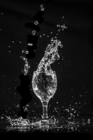 Splash water out of a glass on a black background.の写真素材
