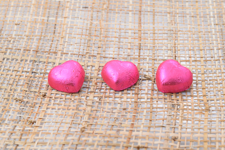 Time for love. pink heart shaped with many small sweet chocolates on burlap background. Indoors...