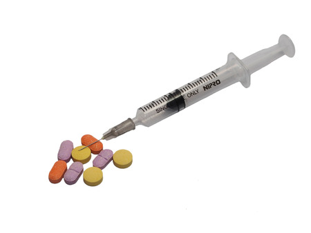 Syringe three mililitres with needle number 27 placed together with multiple color pills, isolation on whiteの写真素材