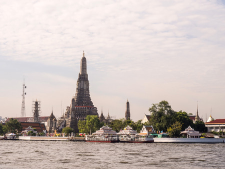 Grand stupa of Dawn temple near Chaophraya river under cloudy sky in Bangkokの写真素材