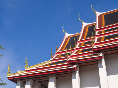 Delicate Thai art at top and roof of church in Wat Pho (Temple of Reclining buddha) under blue sky, Bangkok, Thailandの写真素材