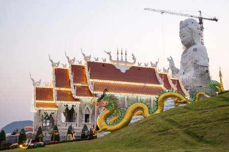 Guan Yim giant statue with Thai temple church and dragon stairs in Thai temple under twilight skyの写真素材